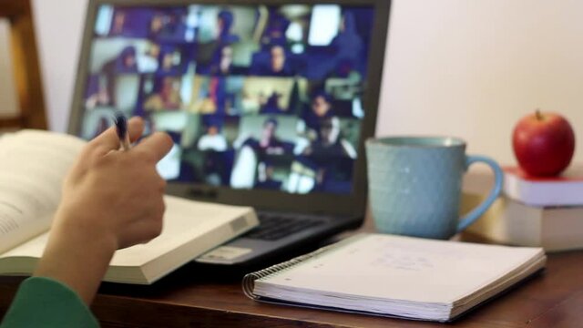 Student taking an online class with his arm raised to ask a question