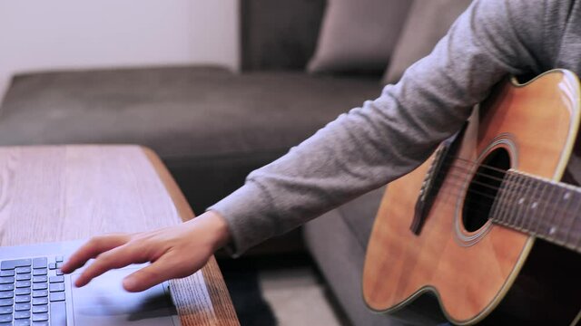 家のソファに座ってギターを練習する日本人の男性