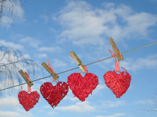 four hearts hanging on a string on the background of blue sky