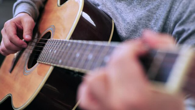 家のソファに座ってギターを練習する日本人の男性