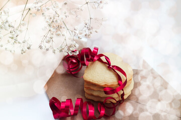 heart-shaped cookies with a red ribbon and a white bouquet of flowers.Space for text.