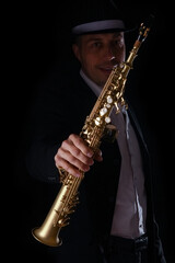 Naklejka premium soprano saxophone in the hands of a guy on a black background