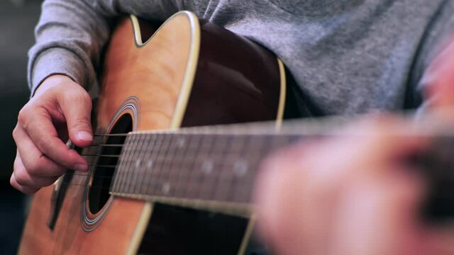 家のソファに座ってギターを練習する日本人の男性