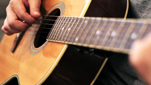 家のソファに座ってギターを練習する日本人の男性