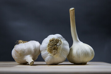 Three heads of garlic on a wooden kitchen board.