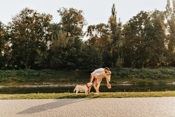 Husband and wife fooling around and dancing tango in park near pond while walking with Labrador