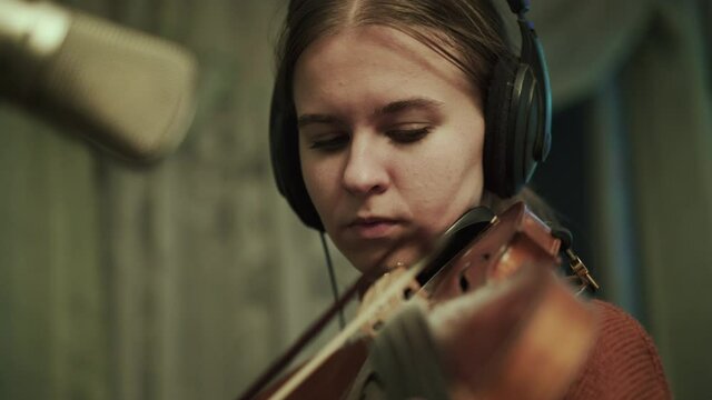 Volinist rehearsing the instrumental melody with headphones at microphone