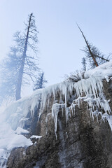 cold crisp icicles hang over a high canyon wall as spring arrives in the deep mountain valleys