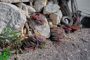 Fishermen stuff and fishnet for fishing standing on the rocks and stones in coast of the lake of...