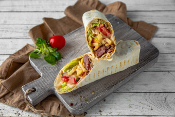 A delicious doner donair kebab wrap with falafel, lettuce, tomato,  onion and sauce.