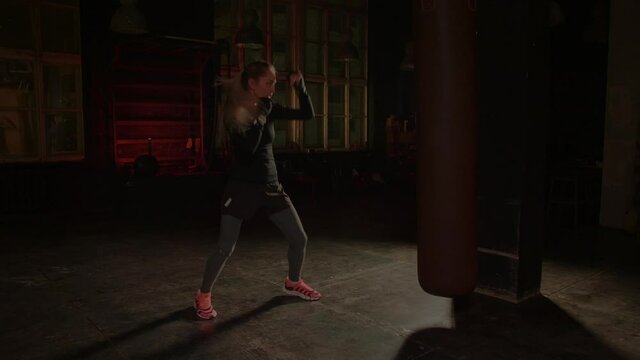 Cool female fighter in boxing gloves trains in the gym. Mixed martial arts