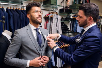Tailor in his menswear store adjusting handkerchief in customers suit pocket