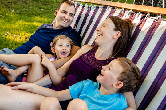 Family laughing while relaxing on hammock during weekend