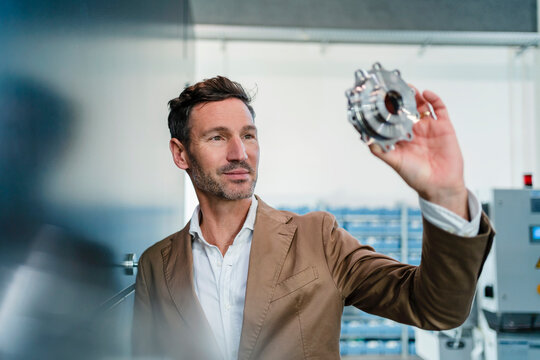 Businessman examining machine part in industry