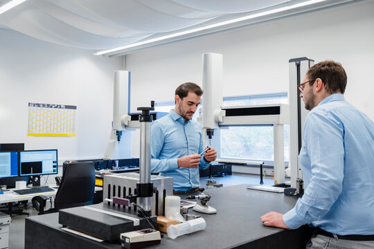 Engineers checking equipment while standing by table in measuring room at office