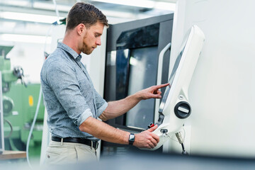 Male entrepreneur using machinery equipment while working in factory