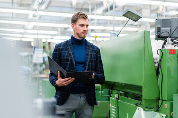 Businessman holding file document examining machinery equipment in factory