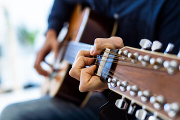 Musician playing acoustic guitar while sitting at studio