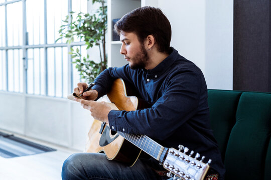 Male composer writing music in note pad while sitting at studio