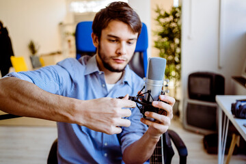 Expertise adjusting microphone stand while sitting at recording studio
