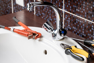 plumbing faucet repair concept. plumber using wrench tool and pliers to adjusting tap leak at bathroom. diy plumber conceptual