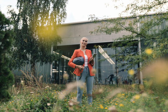 Smiling woman with digital tablet standing in company garden