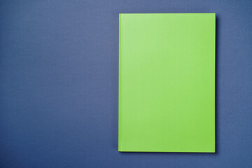 Green Leather notebook on paper intense blue background, notepad mock up, top view shot