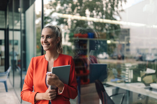 Happy female entrepreneur with digital tablet outside office