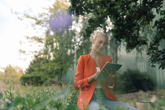 Businesswoman using digital tablet while sitting in company garden