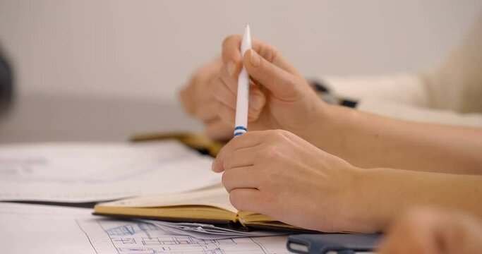 At a meeting in the office, girls are sitting at the table and one is fiddling with a pen out of excitement 