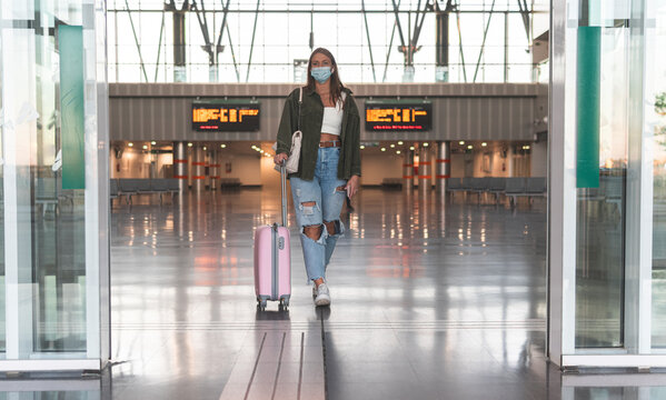 Young woman wearing face mask with suitcase walking at railroad station