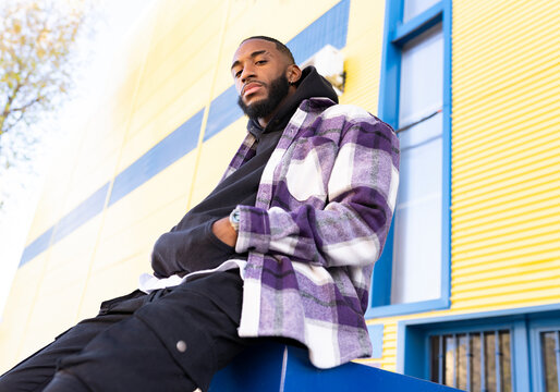 Male rapper with hands in pockets against building exterior