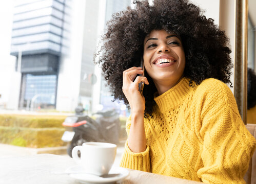 Smiling woman talking on mobile phone while sitting at cafe