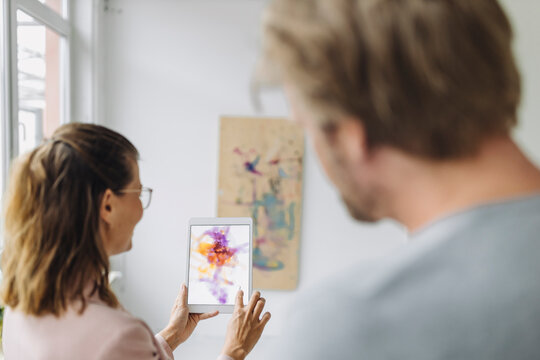 Woman and man using digital tablet in art gallery