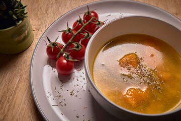 Vegetable soup or broth with pumpkin and chickpeas in a bowl. fine spreading herbs. solid wood background. Healthy, vegan and diet food. tasty recipe