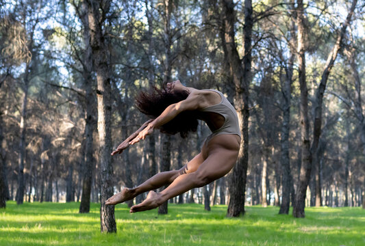 Female dancer jumping during performance in middle of forest