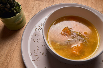 Vegetable soup or broth with pumpkin and chickpeas in a bowl. fine spreading herbs. solid wood background. Healthy, vegan and diet food. tasty recipe