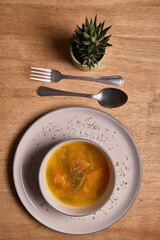 Vegetable soup or broth with pumpkin and chickpeas in a bowl. fine spreading herbs. solid wood background. Healthy, vegan and diet food. tasty recipe