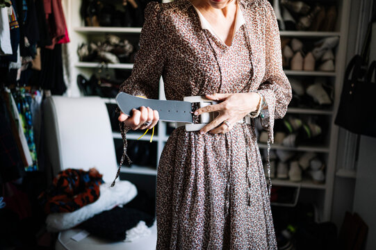 Mid adult woman fastening new belt in wardrobe at home