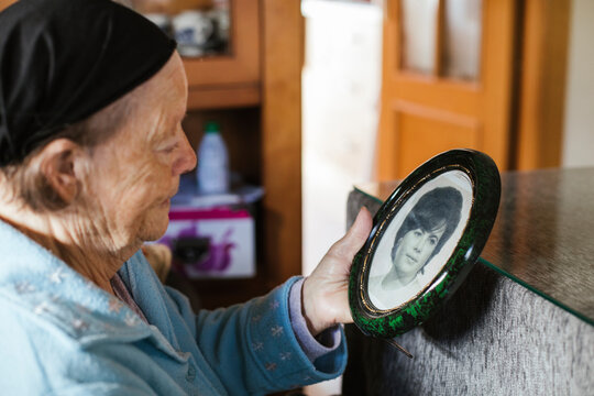 Senior woman looking at old picture frame at home