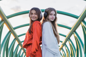 Smiling woman standing back to back with teenage girl on bridge