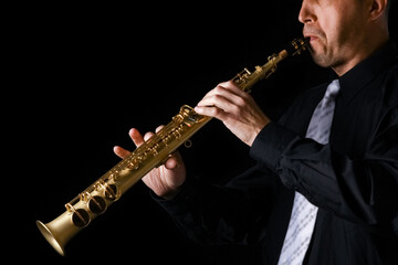 Fototapeta premium soprano saxophone in the hands of a guy on a black background