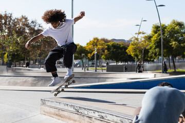 Young sportsman practicing while skateboarding at skateboard park
