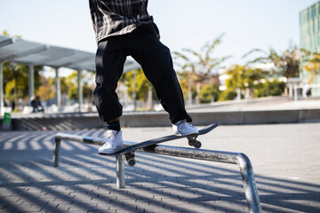 Man balancing while standing with skateboard over hurdle at skateboard park