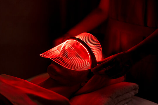 Young woman wearing red mask during rejuvenating treatment at beauty spa