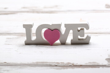 Valentine day love concept. Wooden white lettering love with pink heart on white wooden background