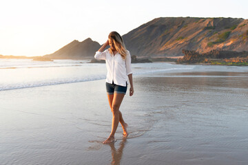 Mid adult woman looking down while walking in water at beach