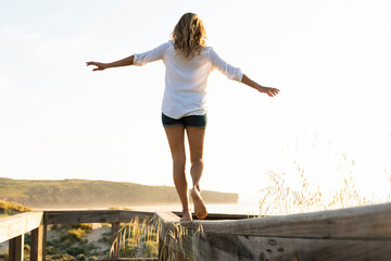 Mid adult woman balancing while walking on wood railing