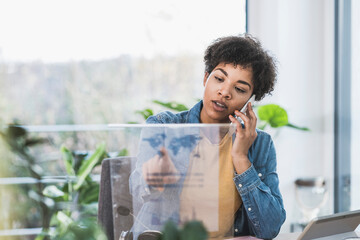 Woman talking on phone and using transparent display at home