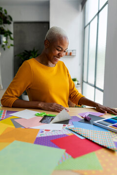 Laughing origami artist working in her studio with colorful paper